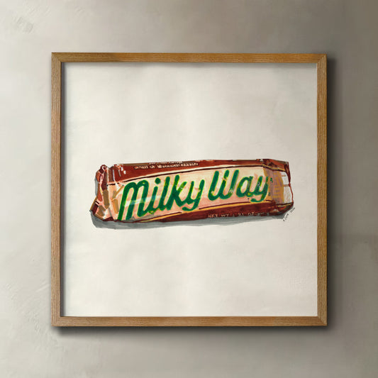 A framed art print featuring a painted illustration of a Milky Way candy bar on an off-white background, enclosed in a light wood frame and mounted on a textured gray wall.