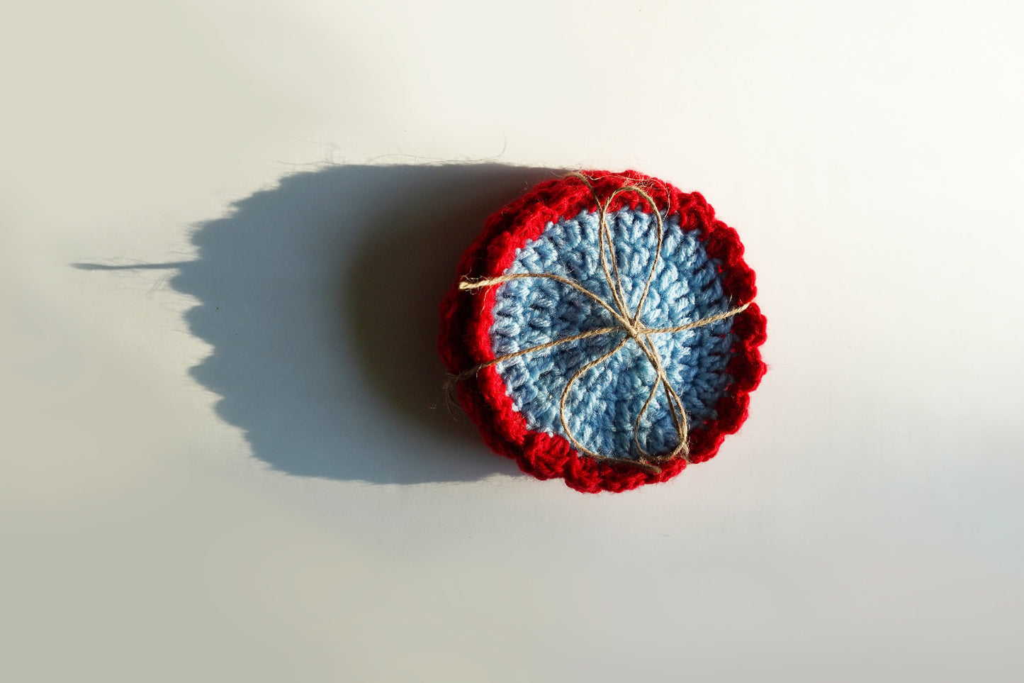 Crocheted red and blue coasterson a light background