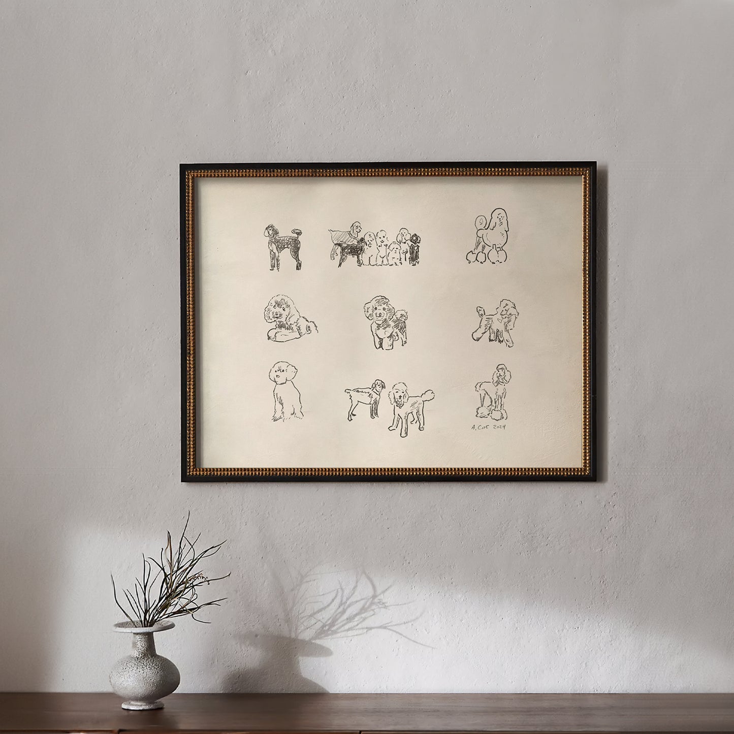 Framed artwork with illustrations of dogs on a beige background, displayed on a wall above a wooden surface.