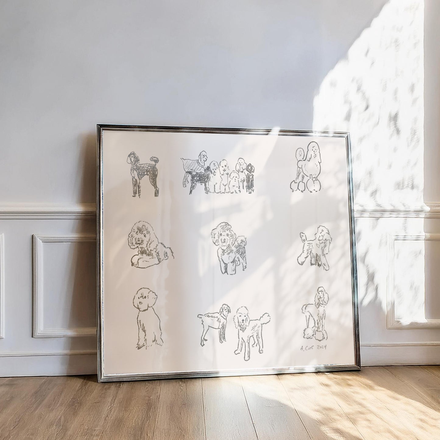 Framed artwork of line-drawn dogs on a white background, leaning against a wall.