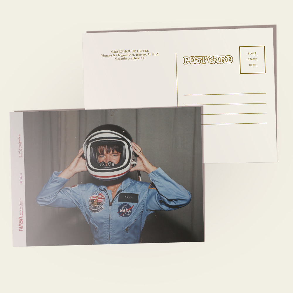 Postcard with Sally Ride in an astronaut suit and helmet on the front, with a plain background.