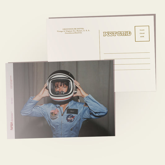 Postcard with Sally Ride in an astronaut suit and helmet on the front, with a plain background.