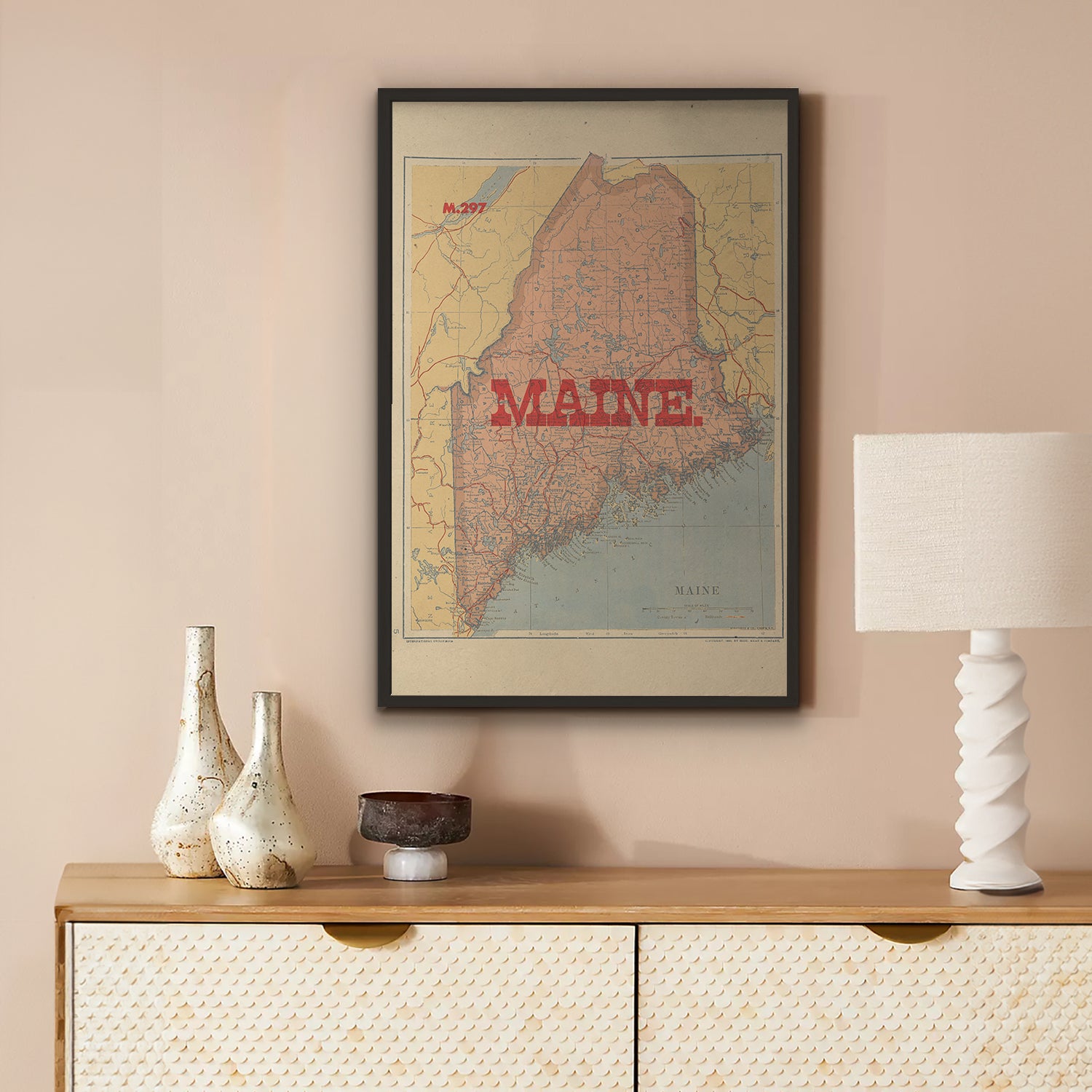Framed map of Maine on a wall above a wooden console table with decorative items.