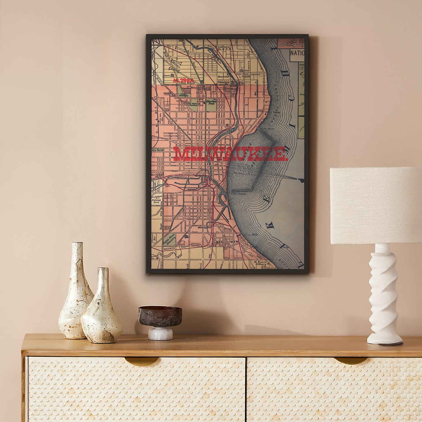 Framed map of Milwaukee on a wall above a wooden console table with decorative items.