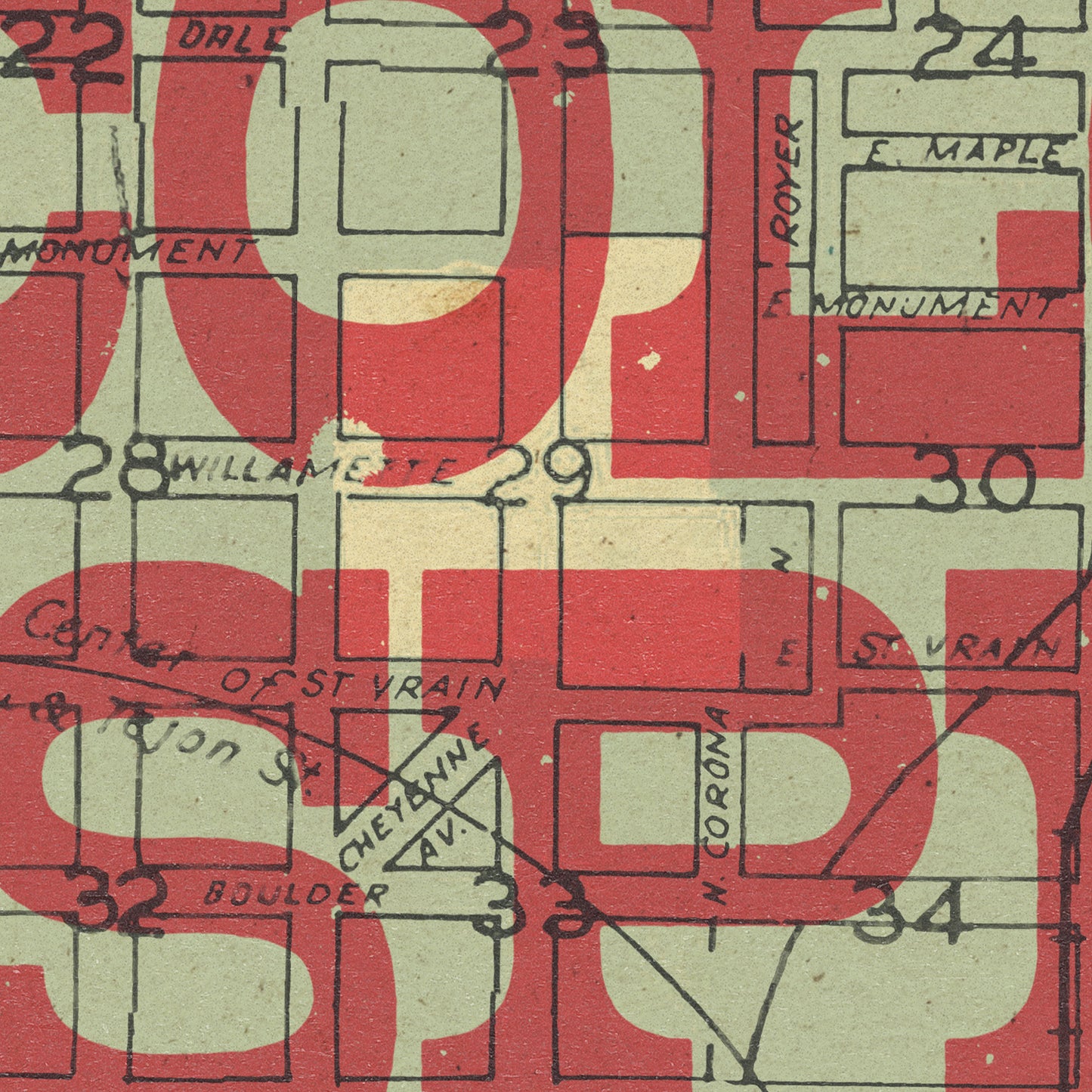 A close-up of a vintage street map print with large red 'COLORADO SPRINGS' lettering overlaid on top of a beige map background, featuring black street lines and handwritten place names such as Monument, Willamette, Boulder, and St. Vrain.