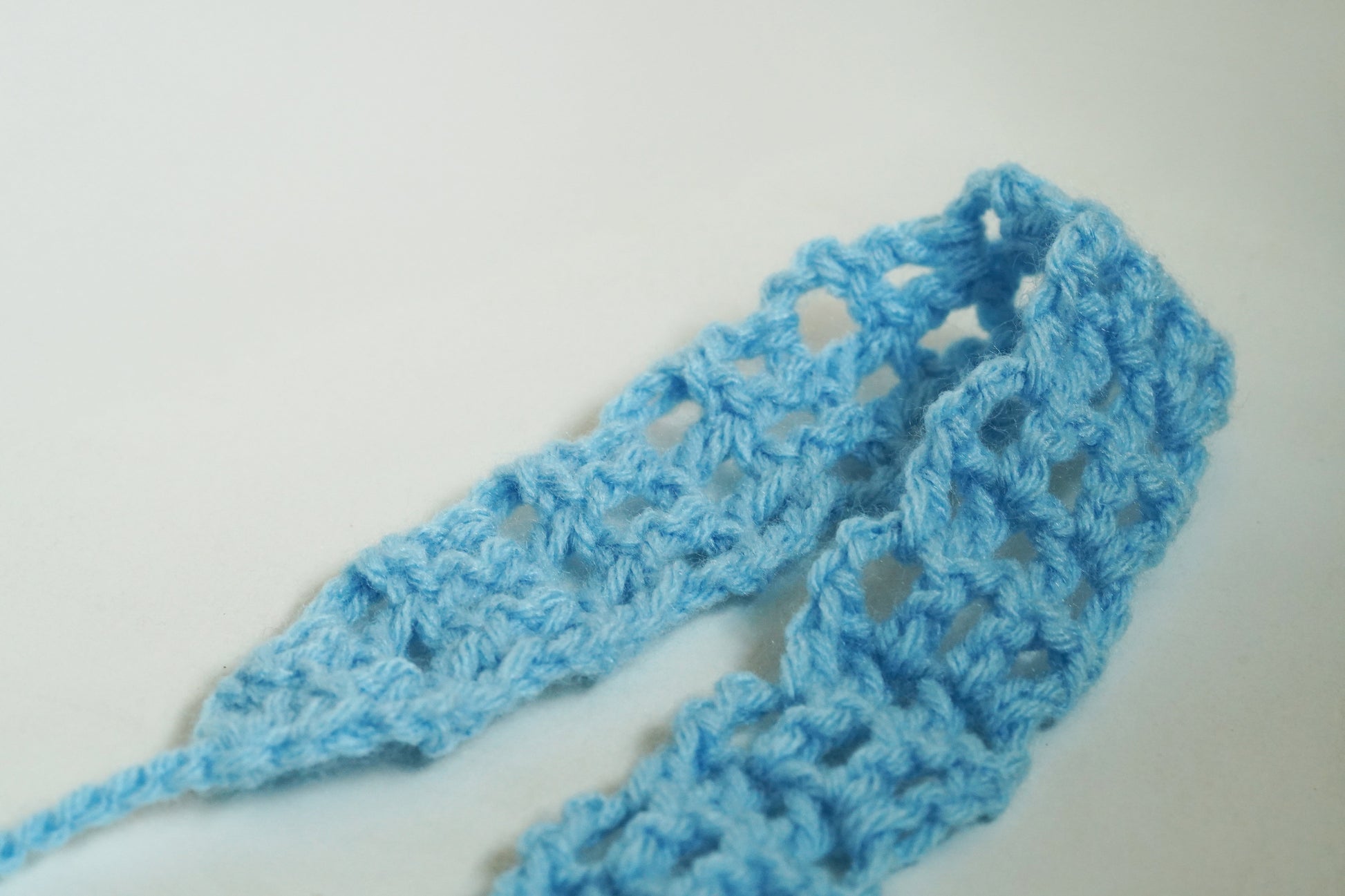 Blue crocheted headband on a white background