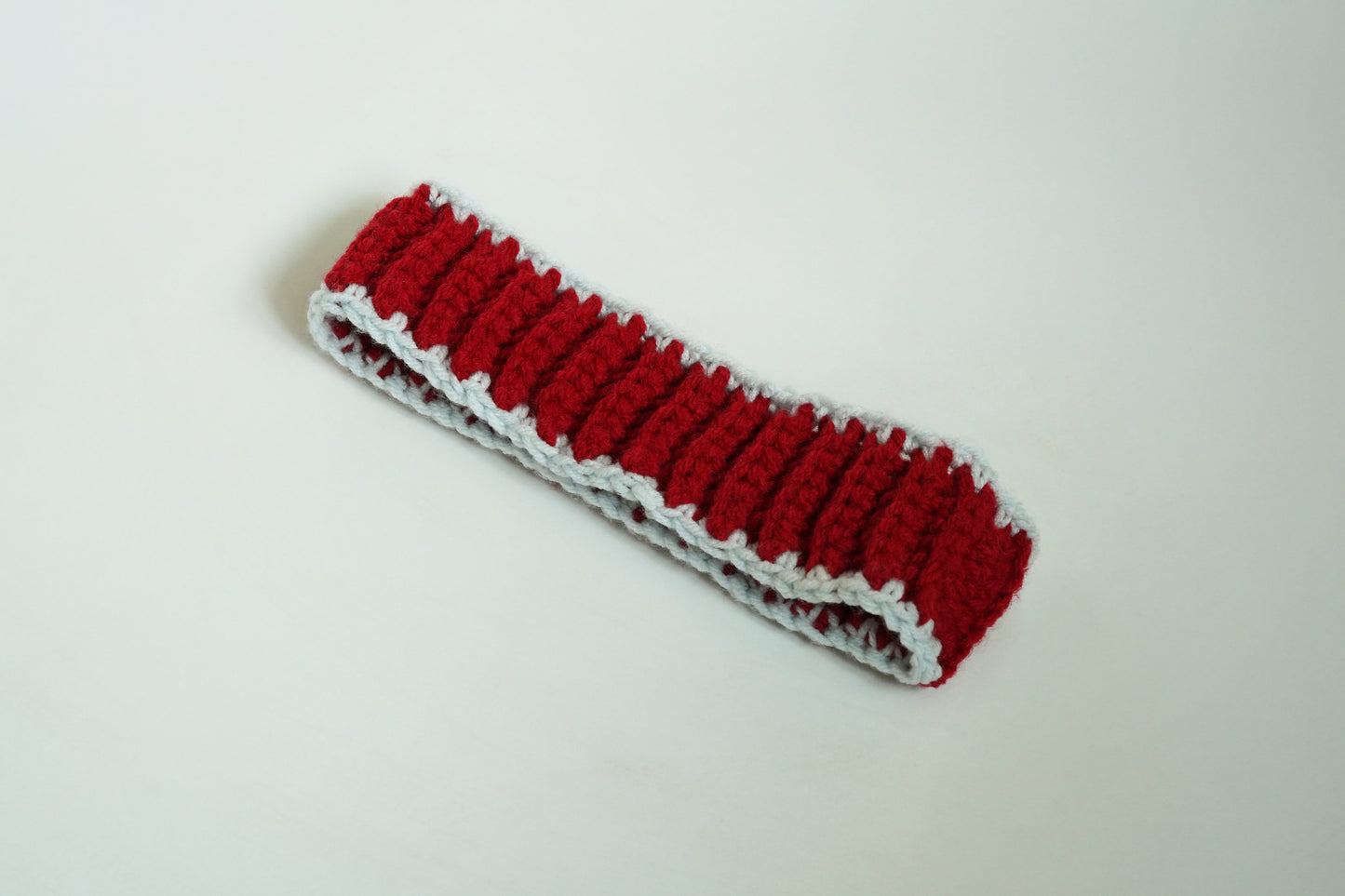 Red crocheted headband on a light gray background