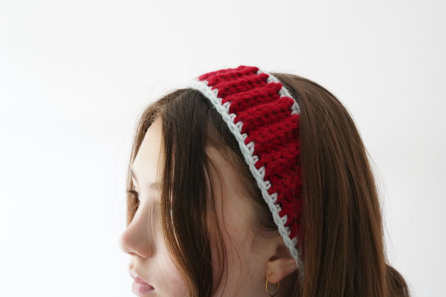 Red and white striped headband worn by a person on a white background