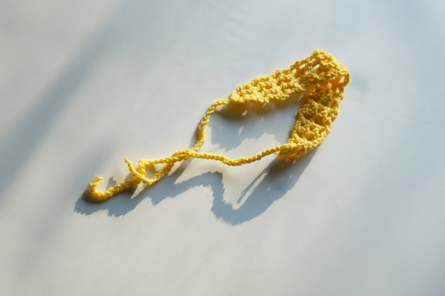 Yellow knitted headband on a light gray surface
