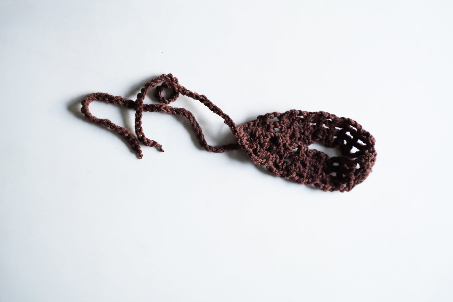 Brown crocheted headband on a white background
