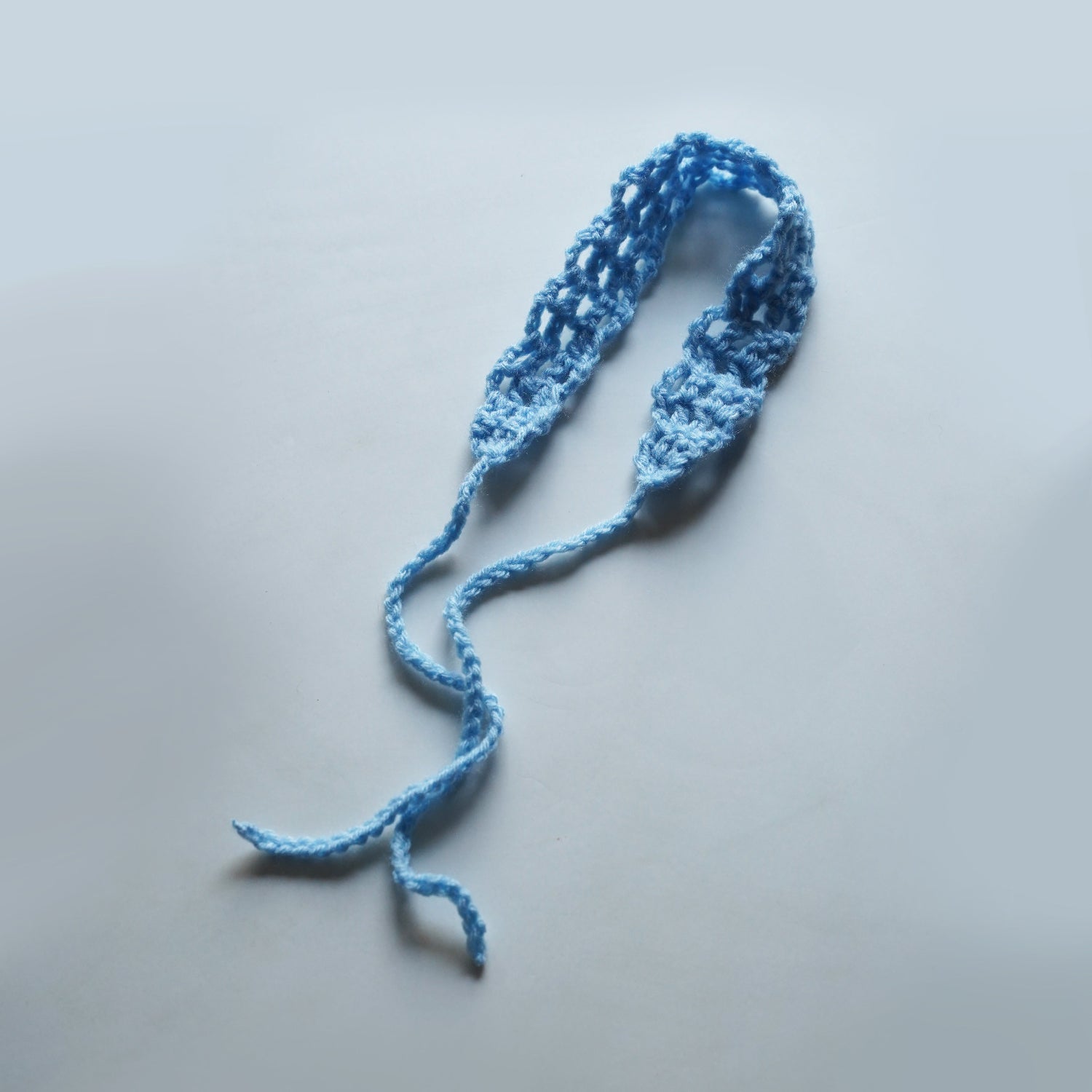 Blue knitted headband on a light gray background