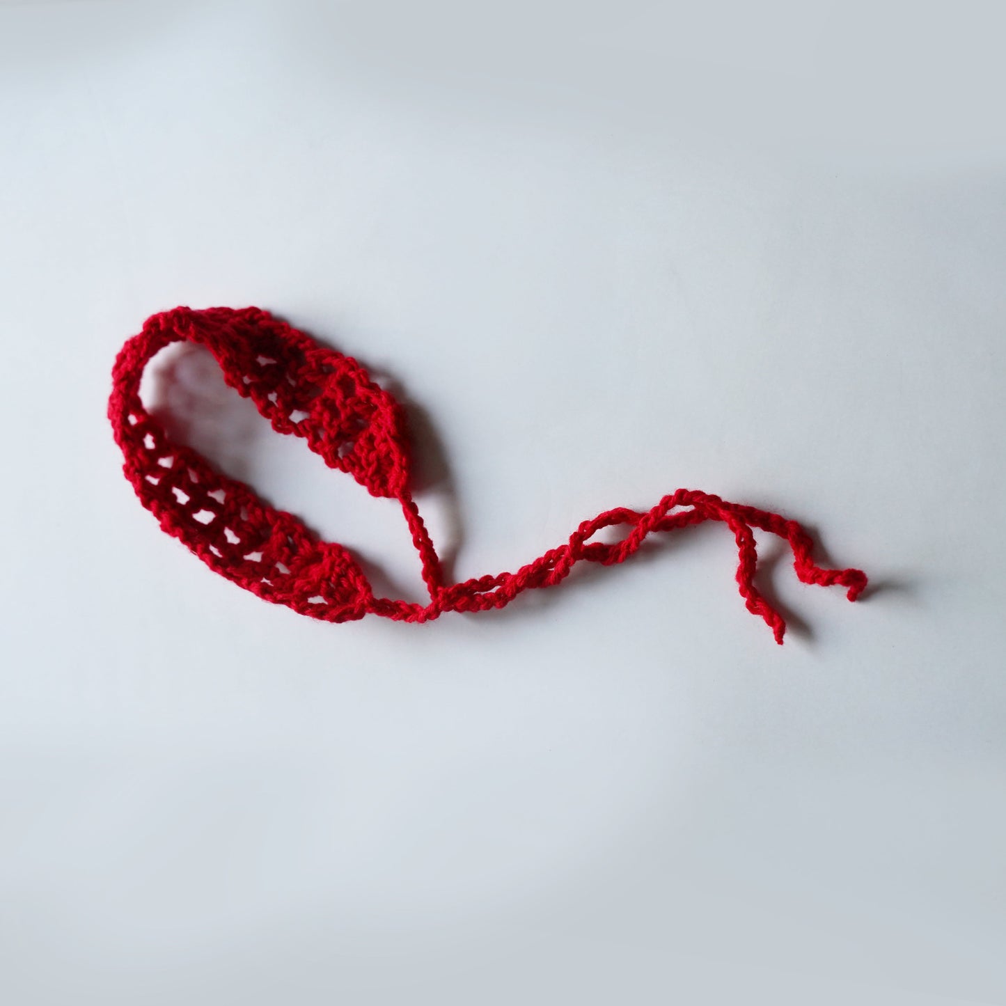 Red knitted headband on a light gray background