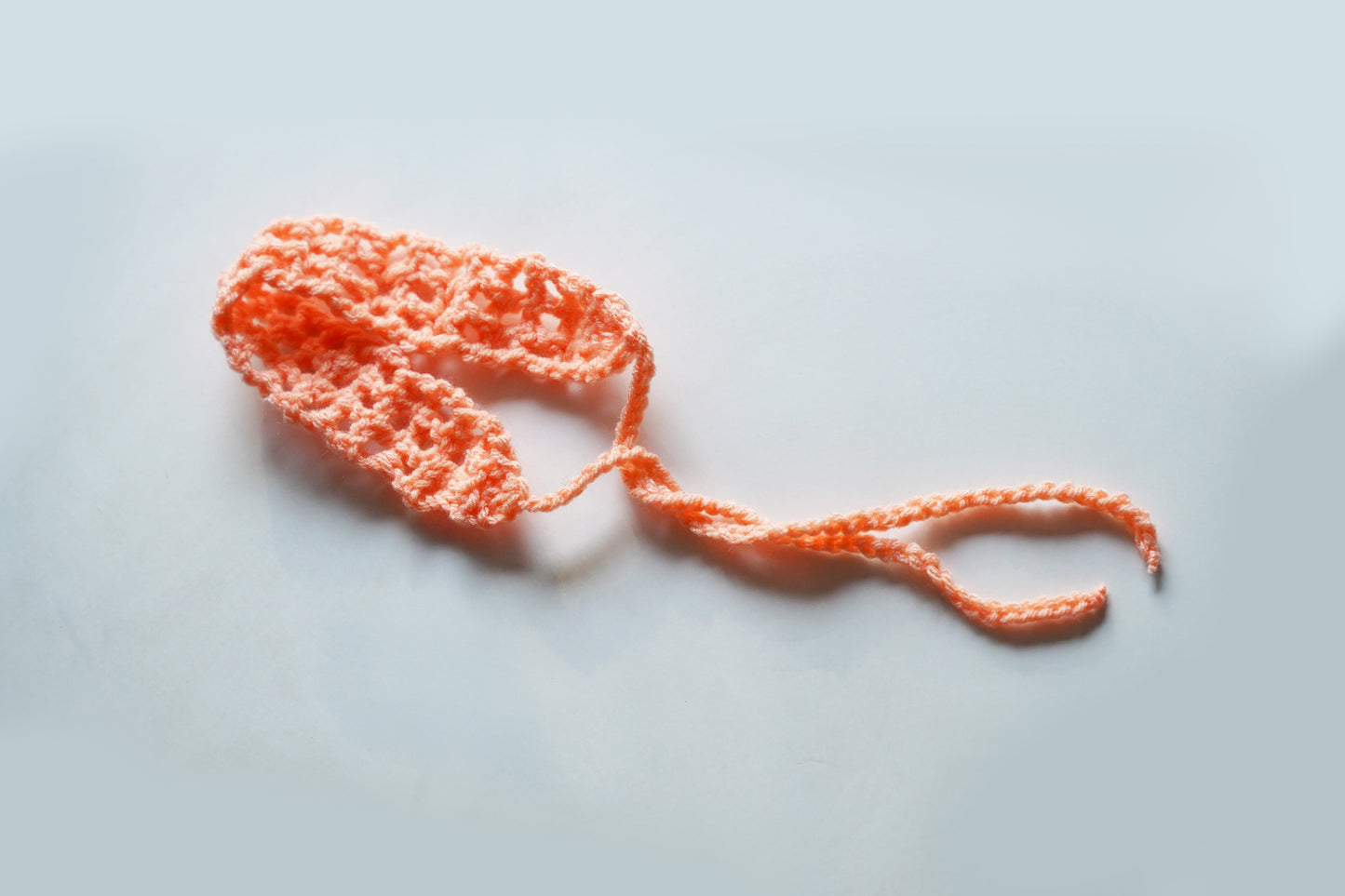 Orange knitted headband on a light gray background