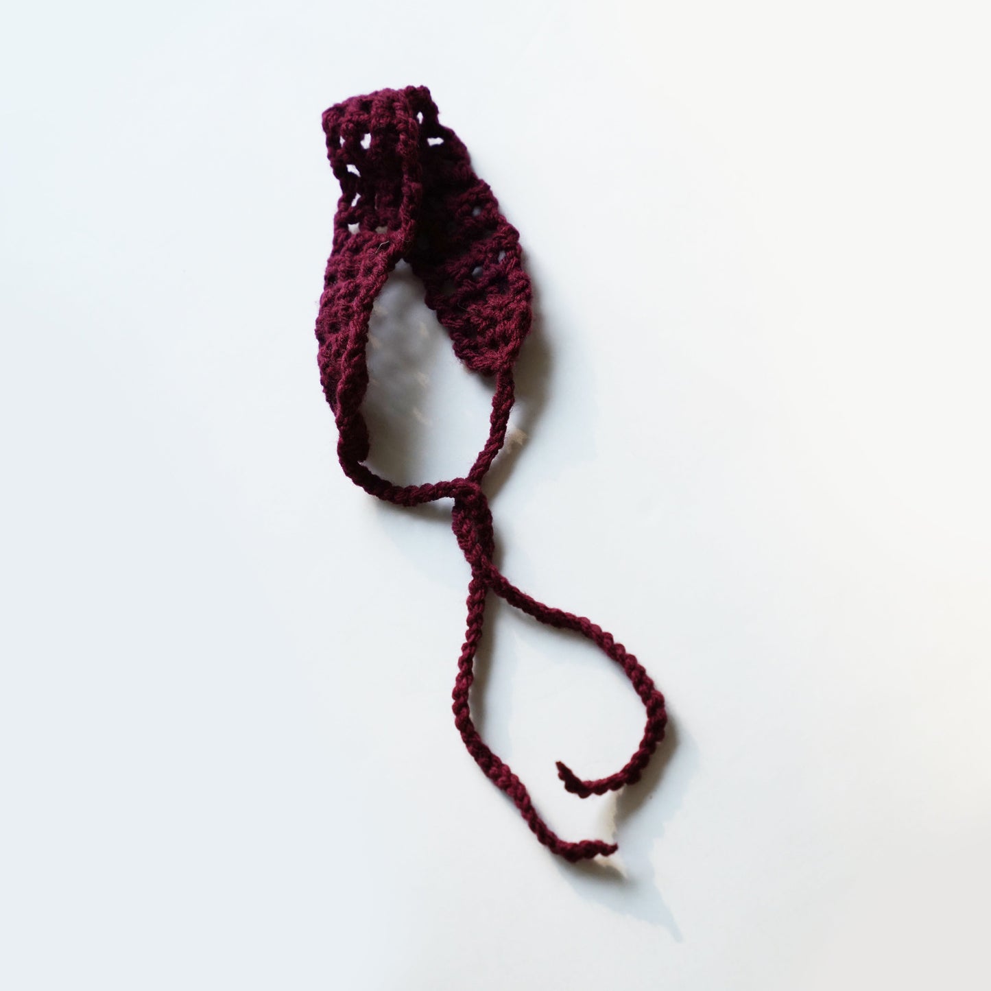 Maroon crocheted headband on a white background