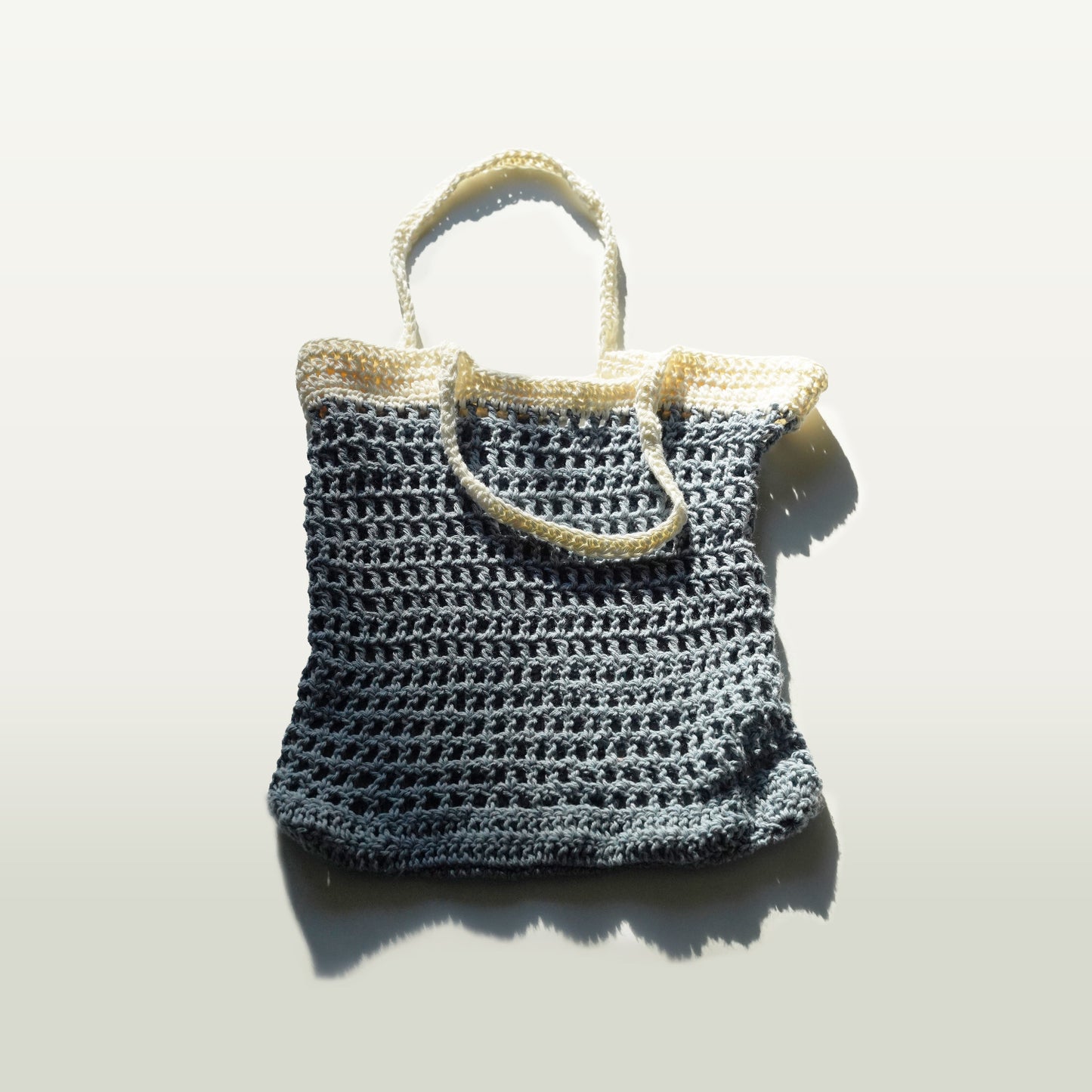 Crocheted bag with beige handles on a white background