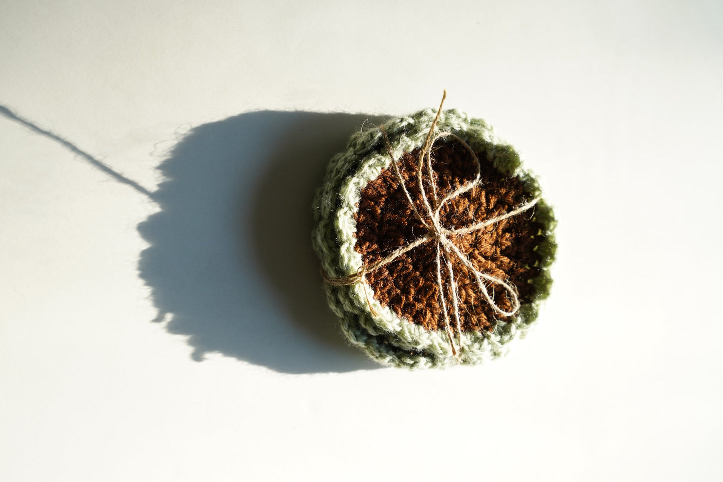 Crocheted coasters with a shadow on a light background