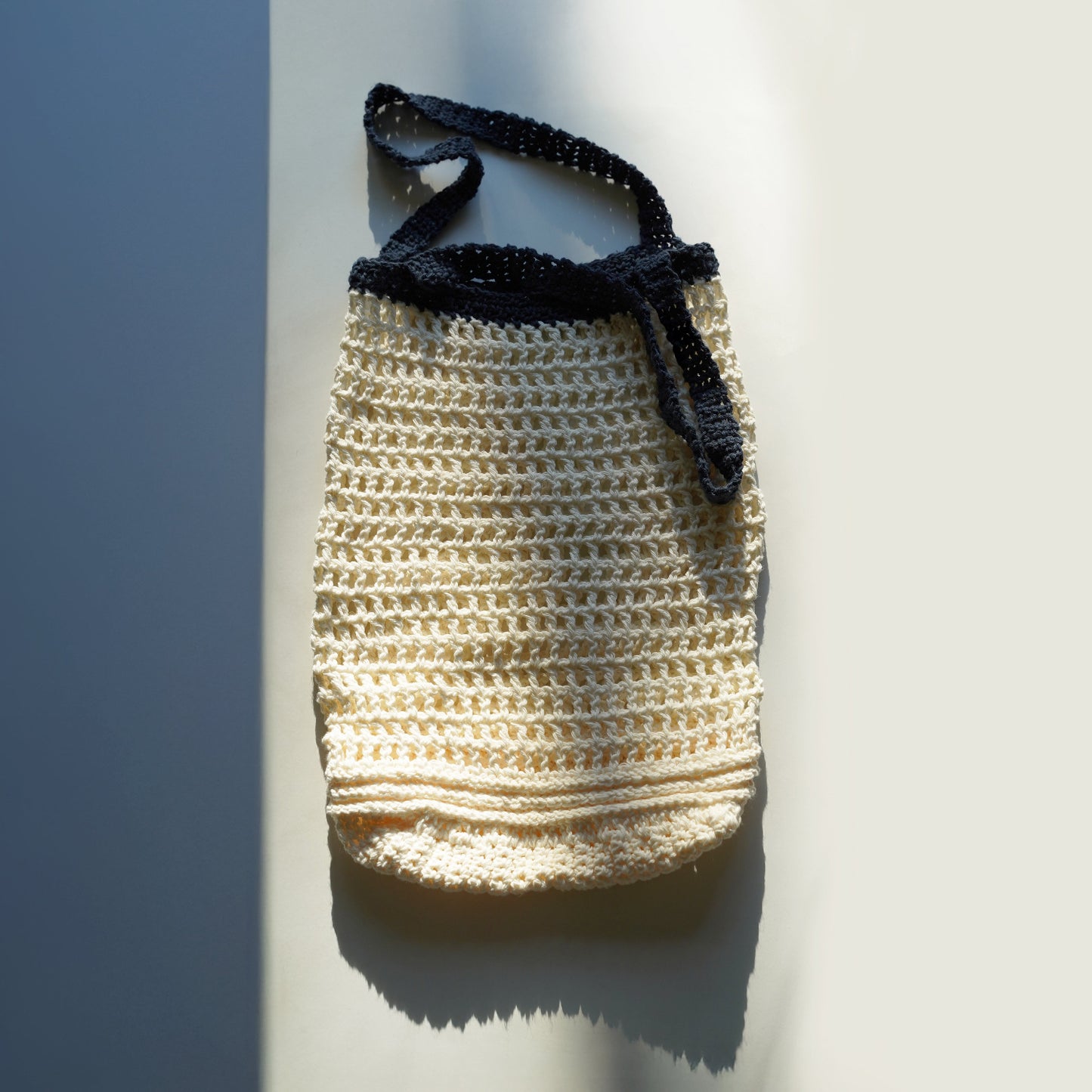 Handmade crochet bag with a navy handle on a light background