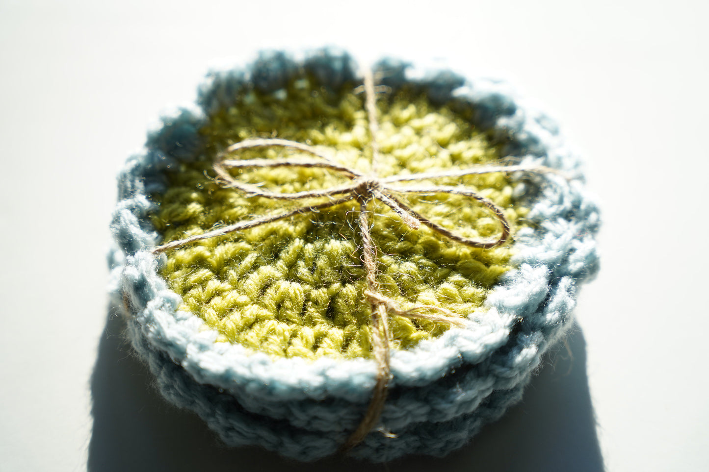 Crocheted coasters tied with a twine bow on a white background