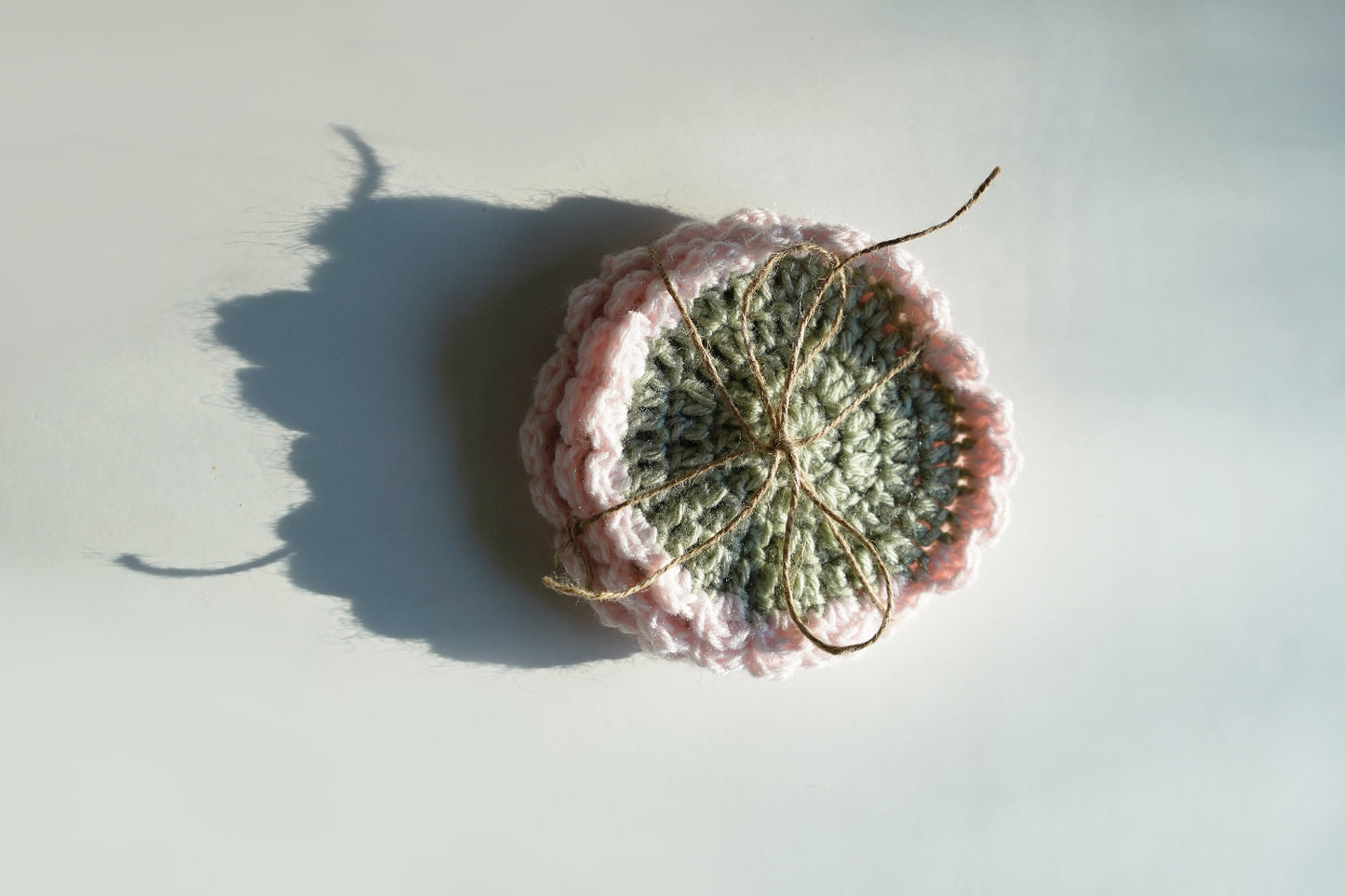 Crocheted green and pink coasters on a light background