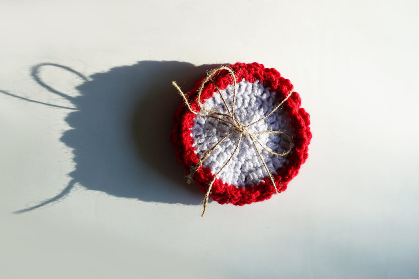 Crocheted coasters with red and white pattern on a light gray background