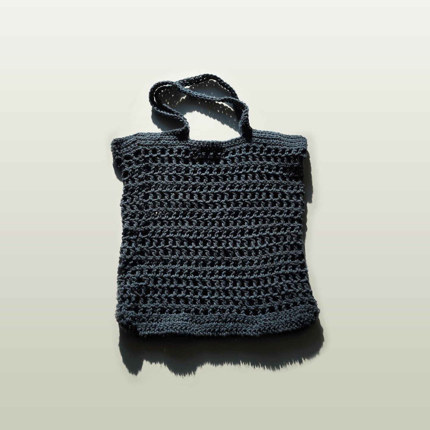 Navy blue woven handbag on a light gray background