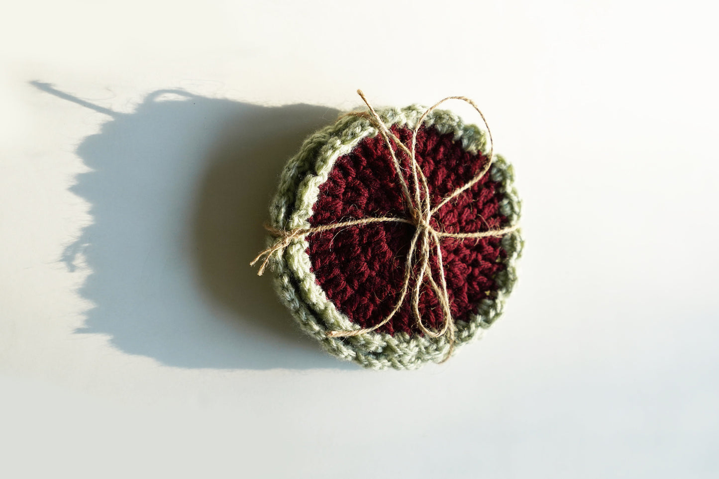 Crocheted coasters with a red center and green edges on a white background